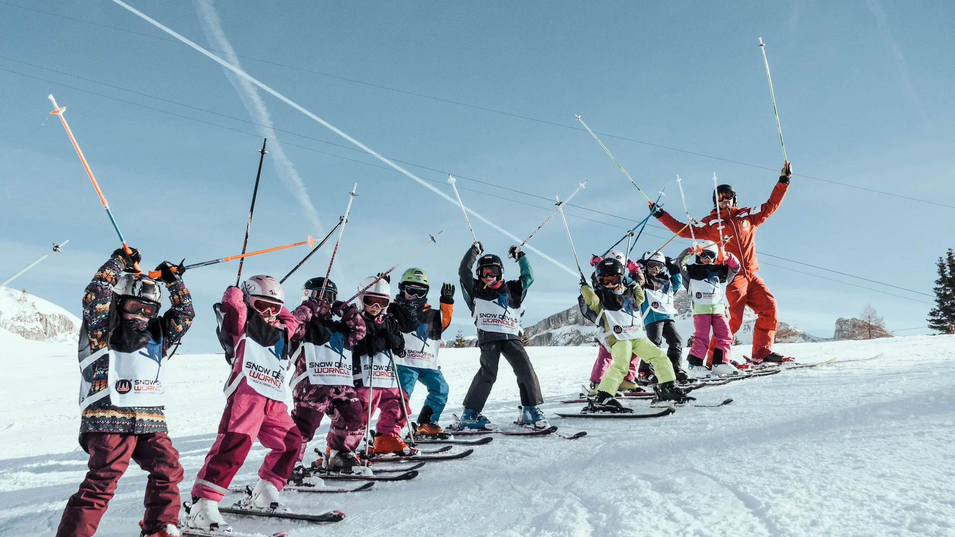Ihr Hotel mit Kinderbetreuung in Tirol Kinder mit Skilehrer machen Skiübungen auf schneebedecktem Hang