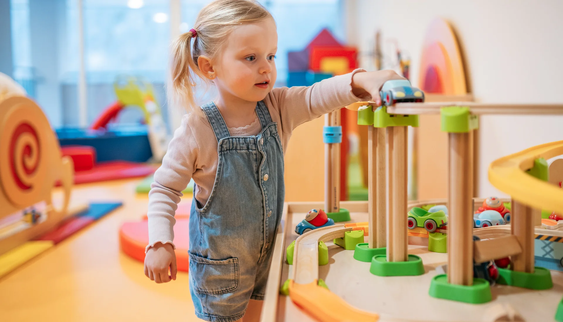Kleines Mädchen spielt mit einer Holzeisenbahn im Spielzimmer