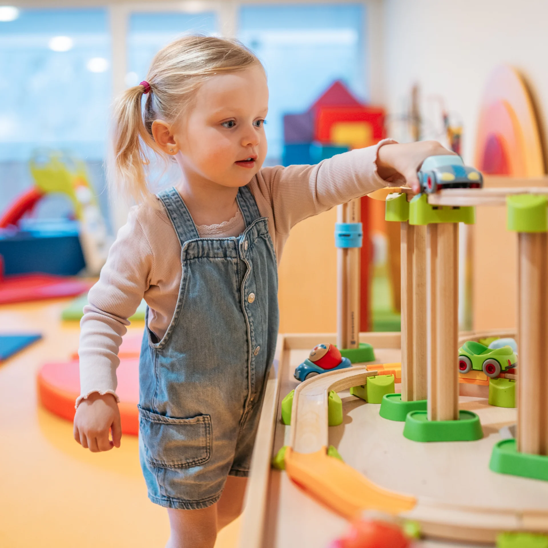 Kleines Mädchen spielt mit einer Holzeisenbahn im Spielzimmer