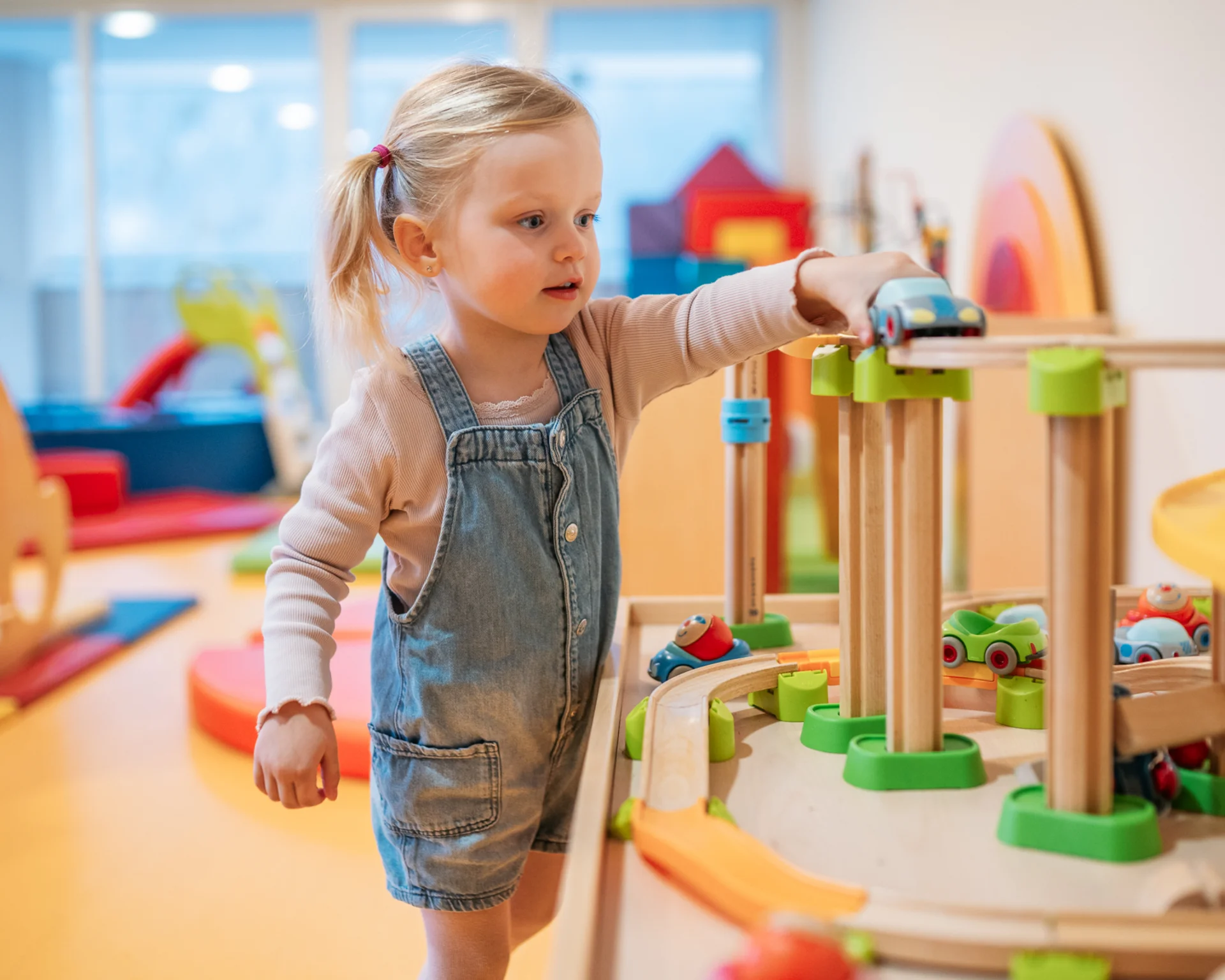 Kleines Mädchen spielt mit einer Holzeisenbahn im Spielzimmer