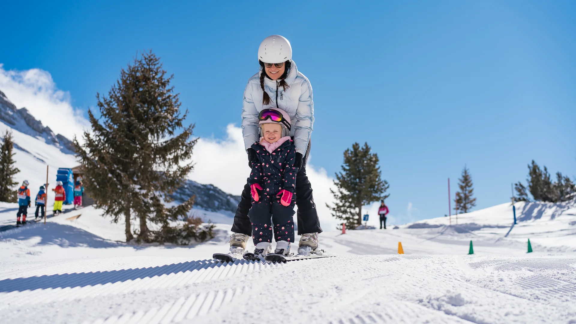 The family resort in Buchau for quality time in Tyrol Adult and child learning to ski together on snowy slope on a sunny day