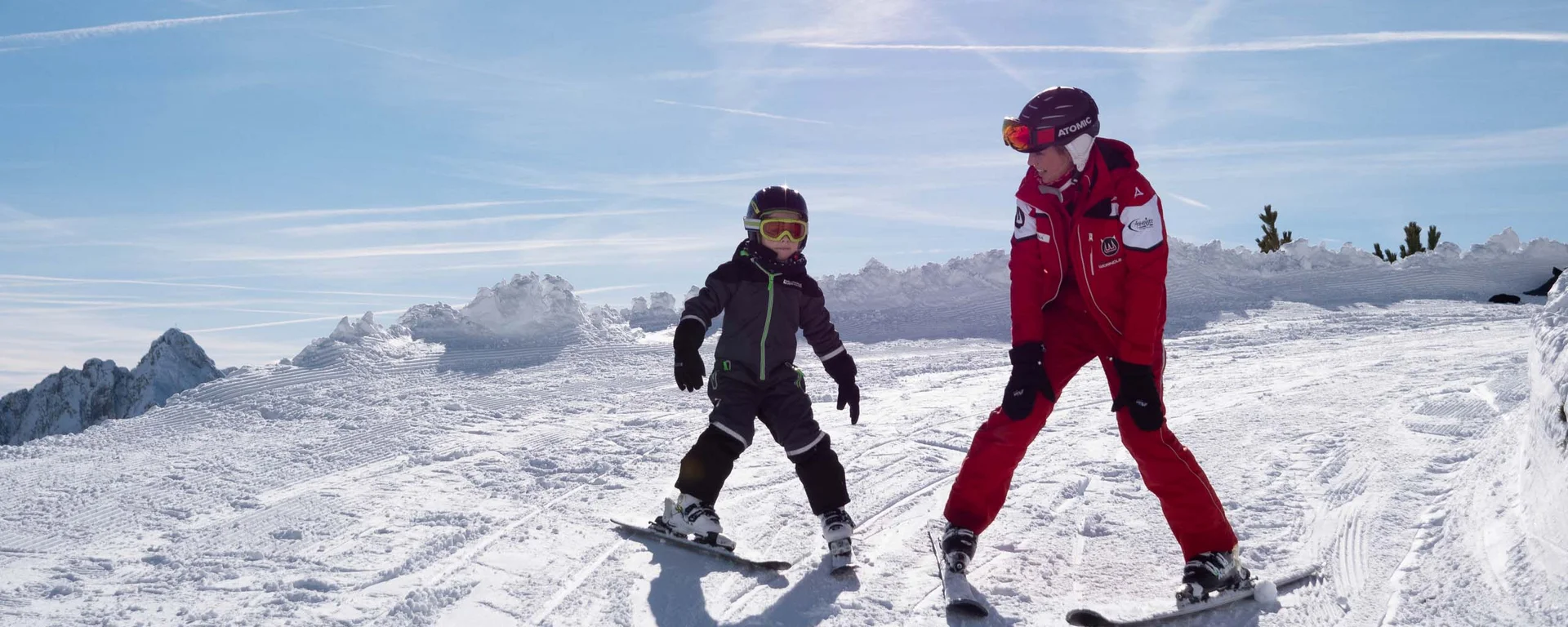 Kind und Skilehrer beim Skifahren auf verschneiter Piste bei Sonnenschein