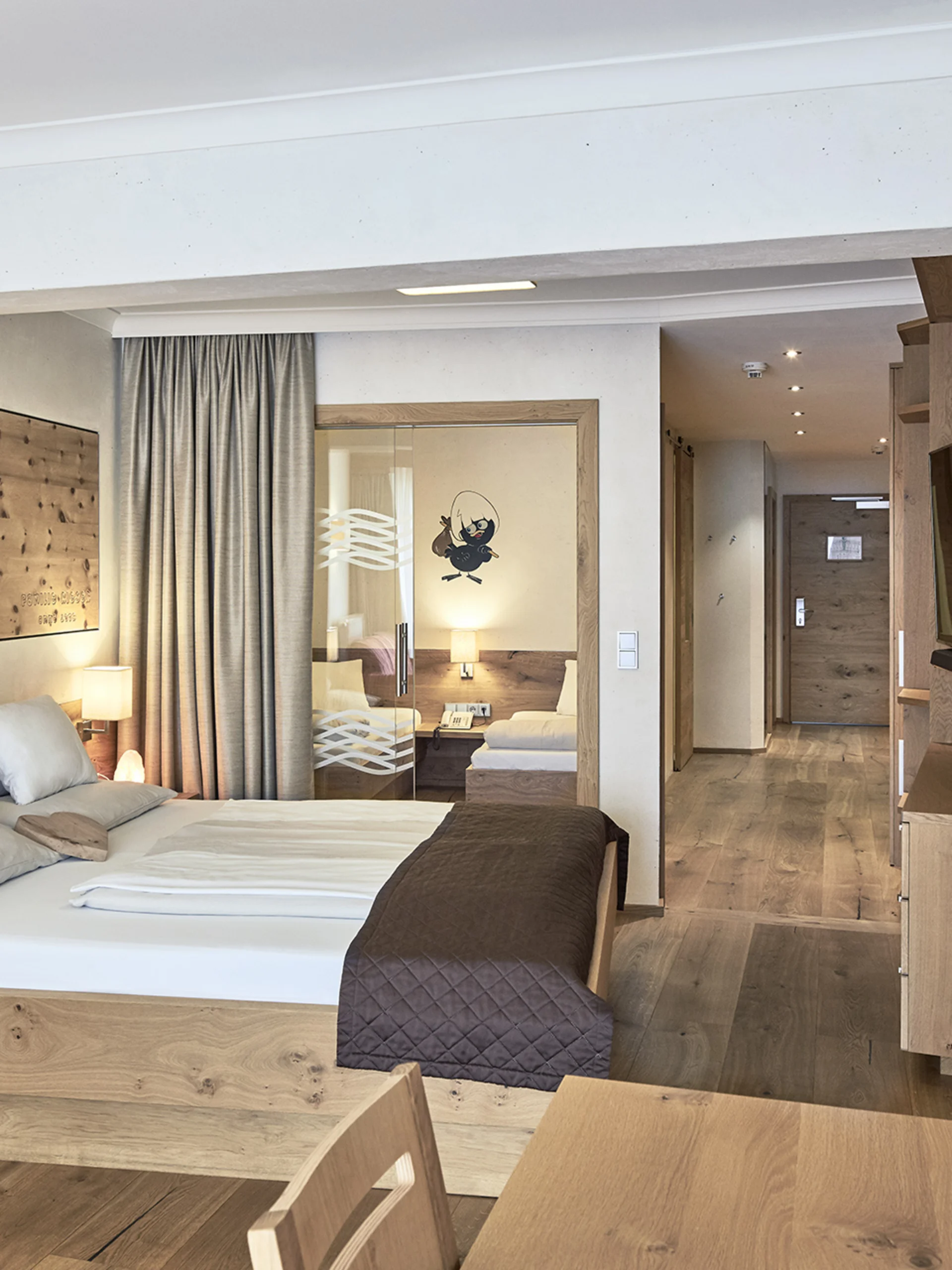 Modernes Hotelzimmer mit Holzmöbeln, Doppelbett und Flur zum Eingang