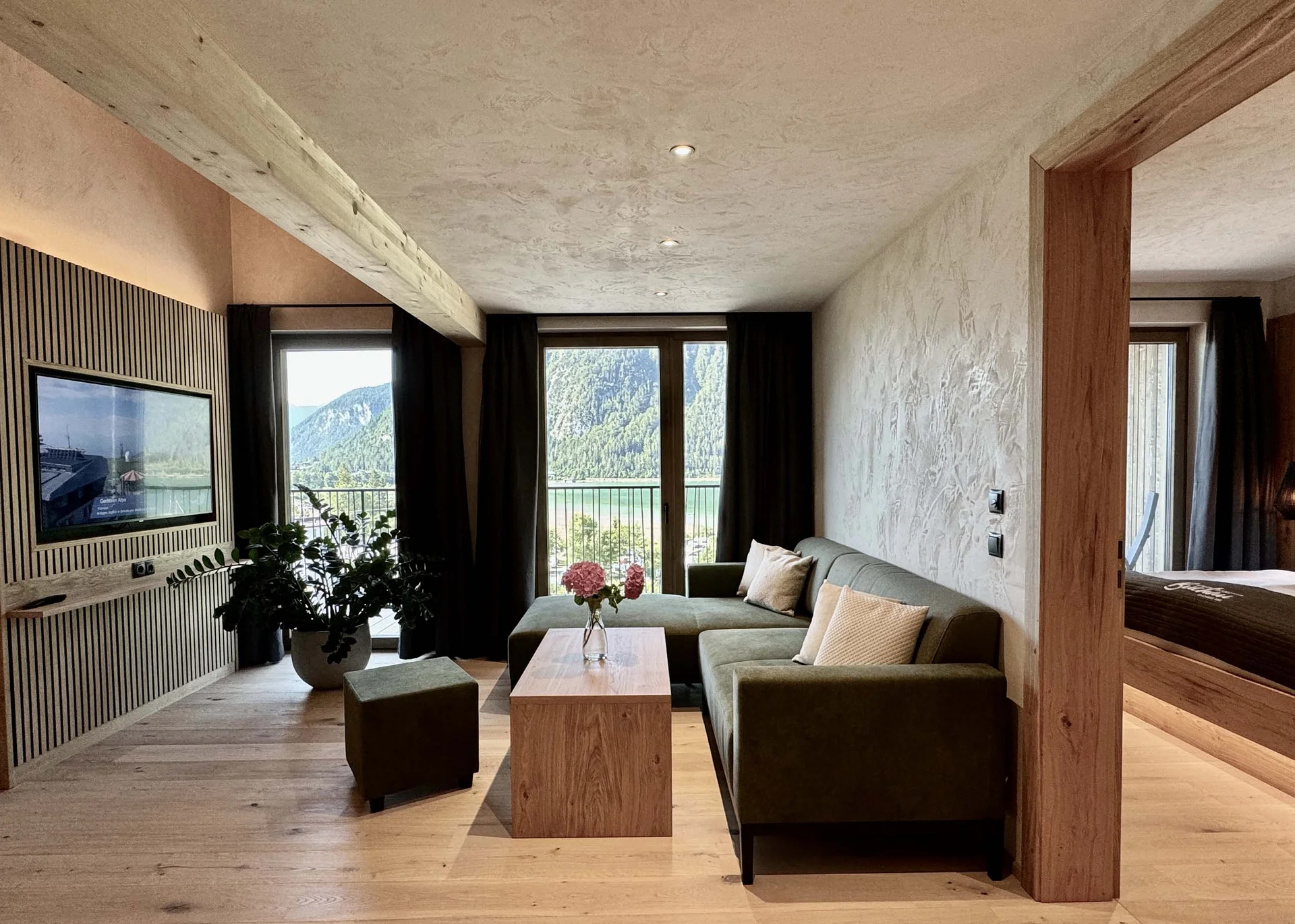 Moderne Wohnung mit grünem Sofa, Holztisch und Balkon mit Bergblick