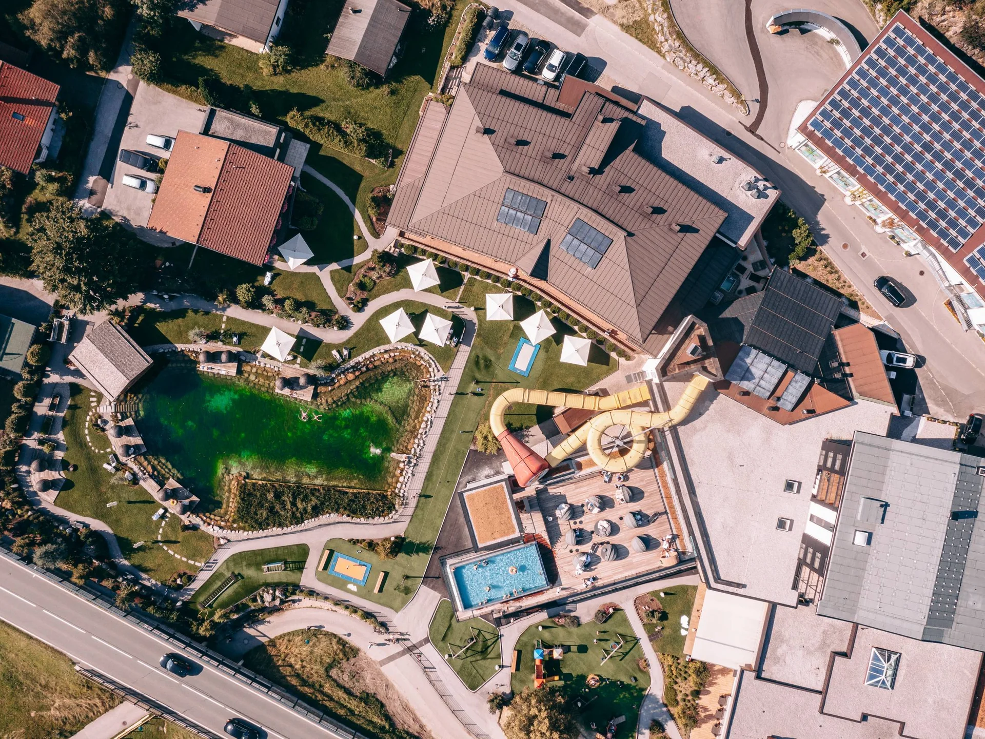 Luftaufnahme eines Freizeitbads mit Wasserrutschen, Schwimmbecken und Grünflächen