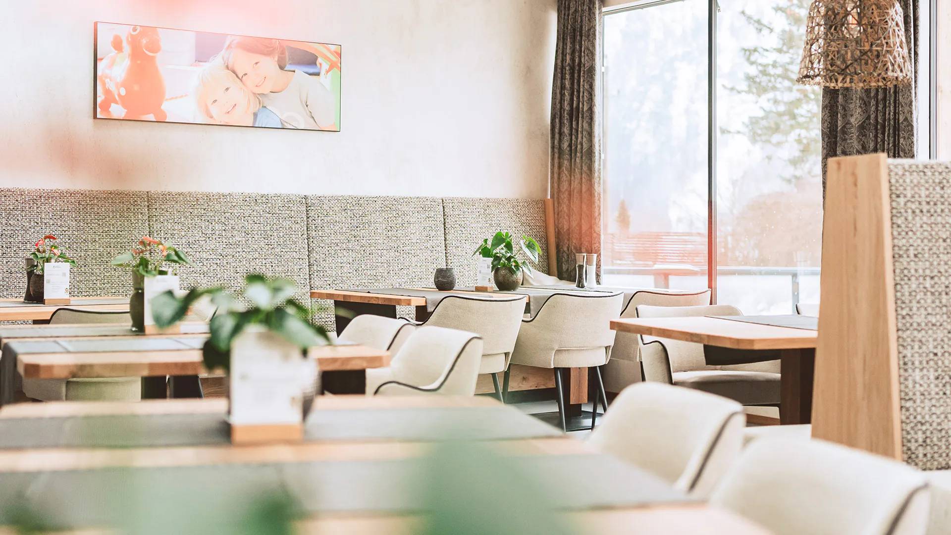Helles modernes Restaurant mit Grau- und Holztönen, Pflanzen und Bilderrahmen an der Wand
