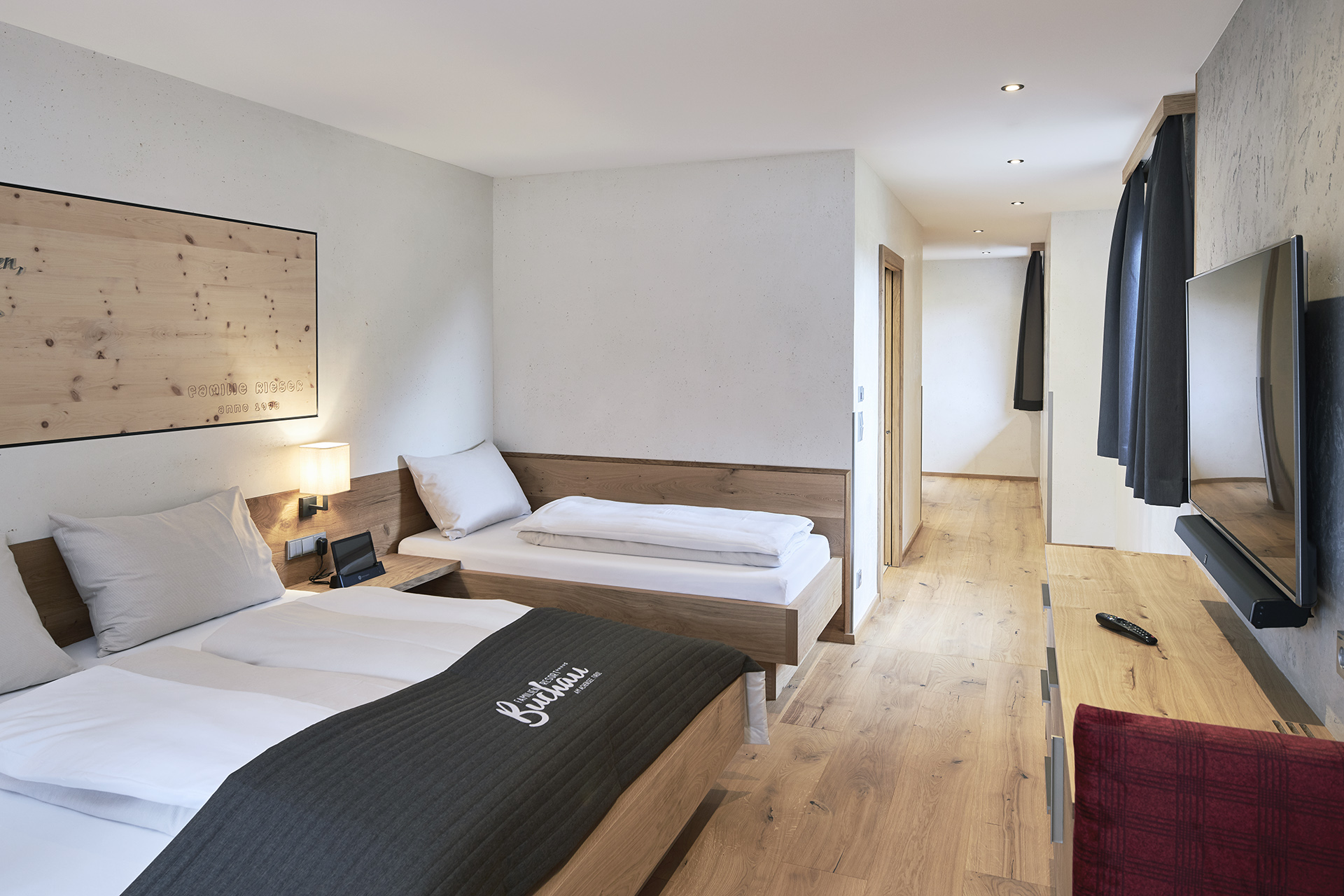 Modernes Hotelzimmer mit zwei Betten, Fernseher und Holzmöbeln